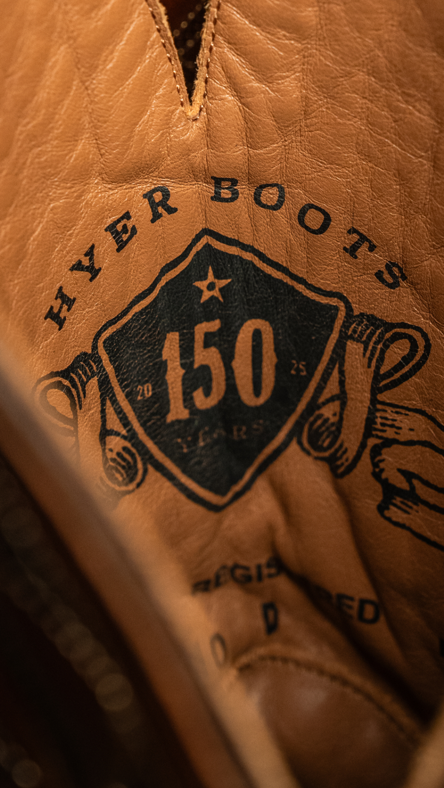 Close-up of a brown leather boot with 'Hyer Boots' branding and '150' on a dark background.