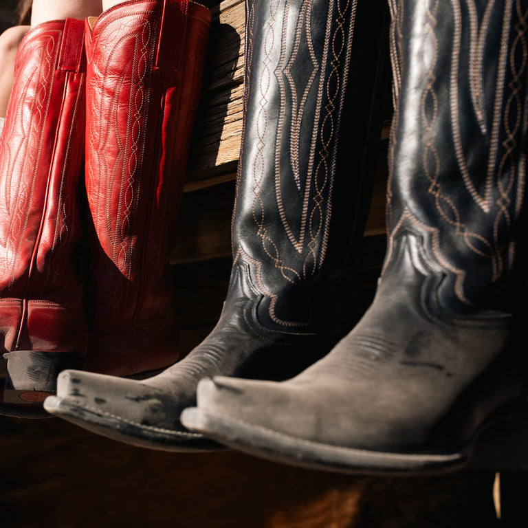 Close-up of red and black cowboy boots with intricate designs.