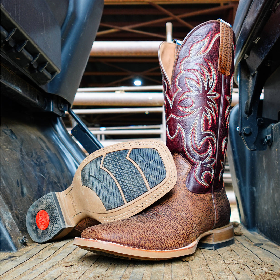 Brown cowboy boot with intricate design on a wooden surface