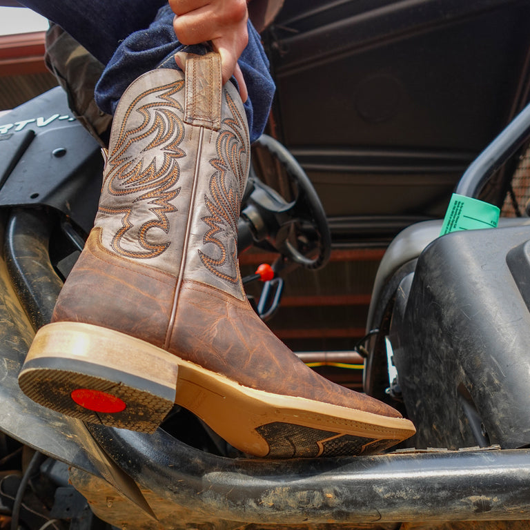Brown cowboy boot with intricate design on a vehicle seat