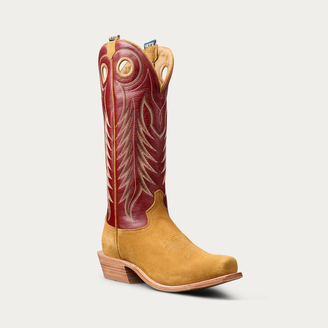 A single western cowboy boot shown in a side profile on a light gray background. The boot features a tan suede lower section and a red leather shaft with beige embroidered stitching and decorative details.