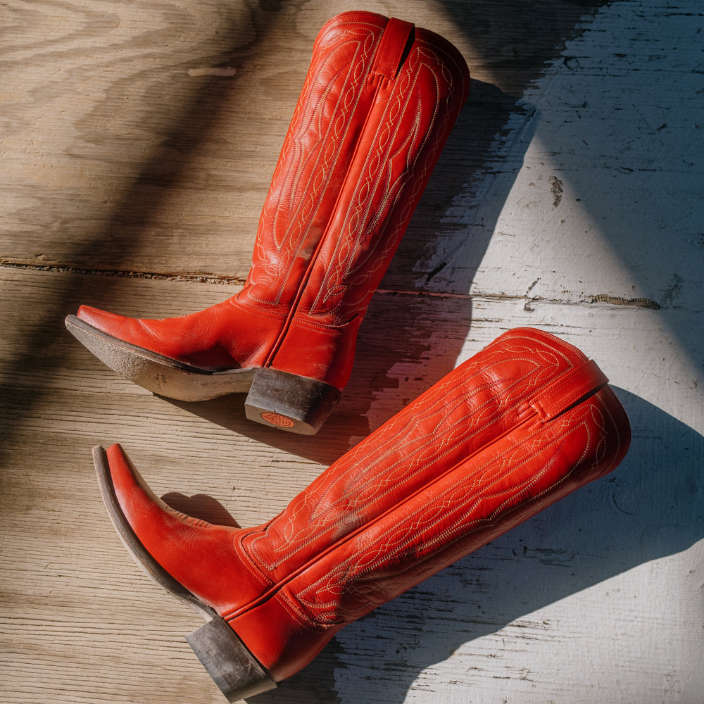 Pair of red cowboy boots on a wooden surface