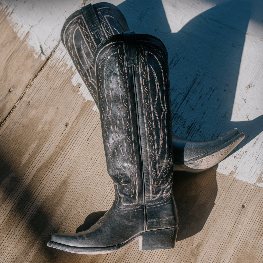 Pair of black cowboy boots on a wooden floor