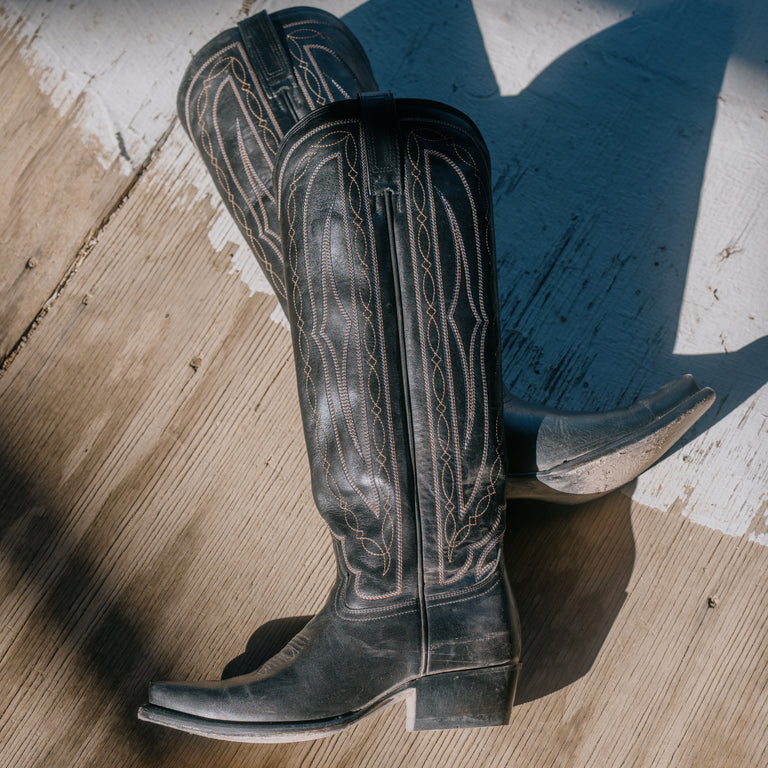 Pair of black cowboy boots on a wooden floor