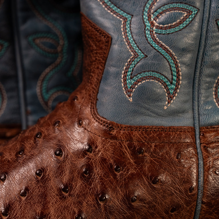 Close-up of a western boot featuring a brown full quill ostrich leather vamp and a blue leather shaft with turquoise embroidered detailing.