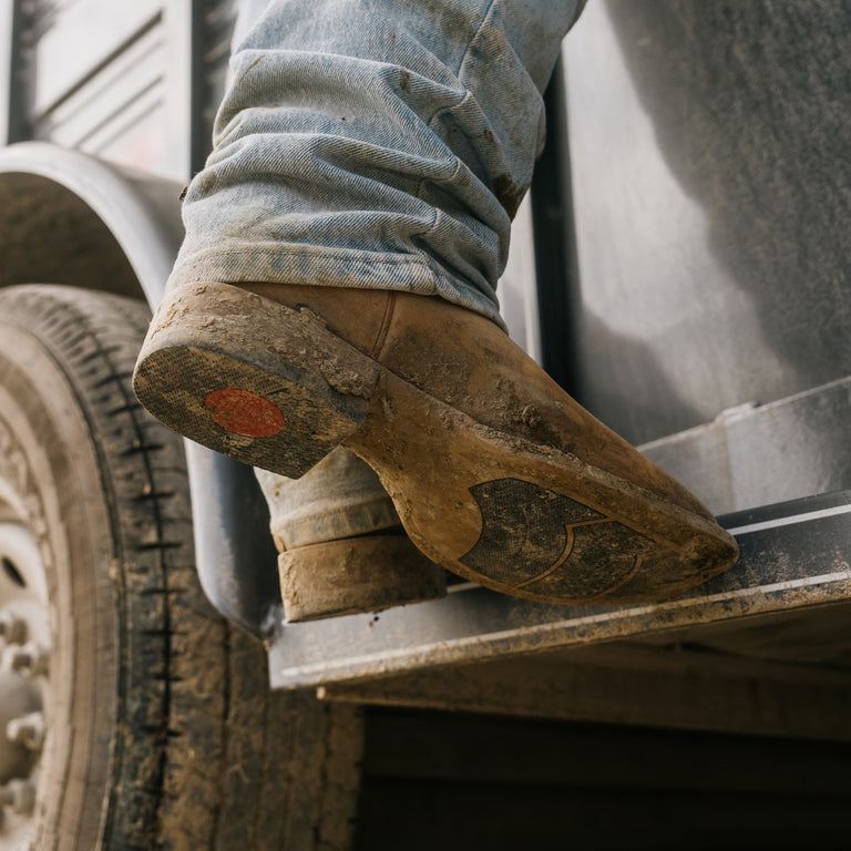 Person wearing work boots stepping onto a truck bed