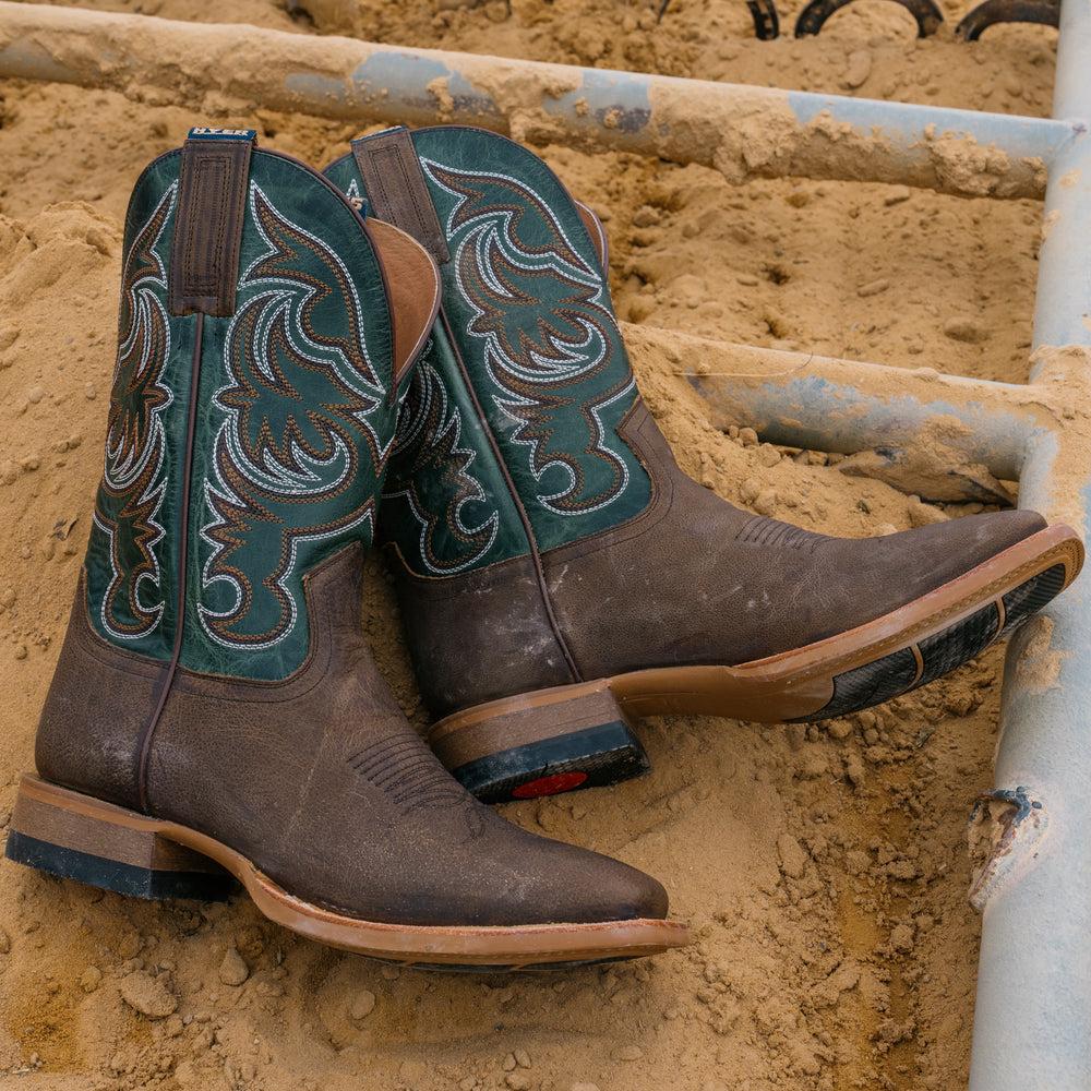 Brown cowboy boots with intricate designs on a sandy background
