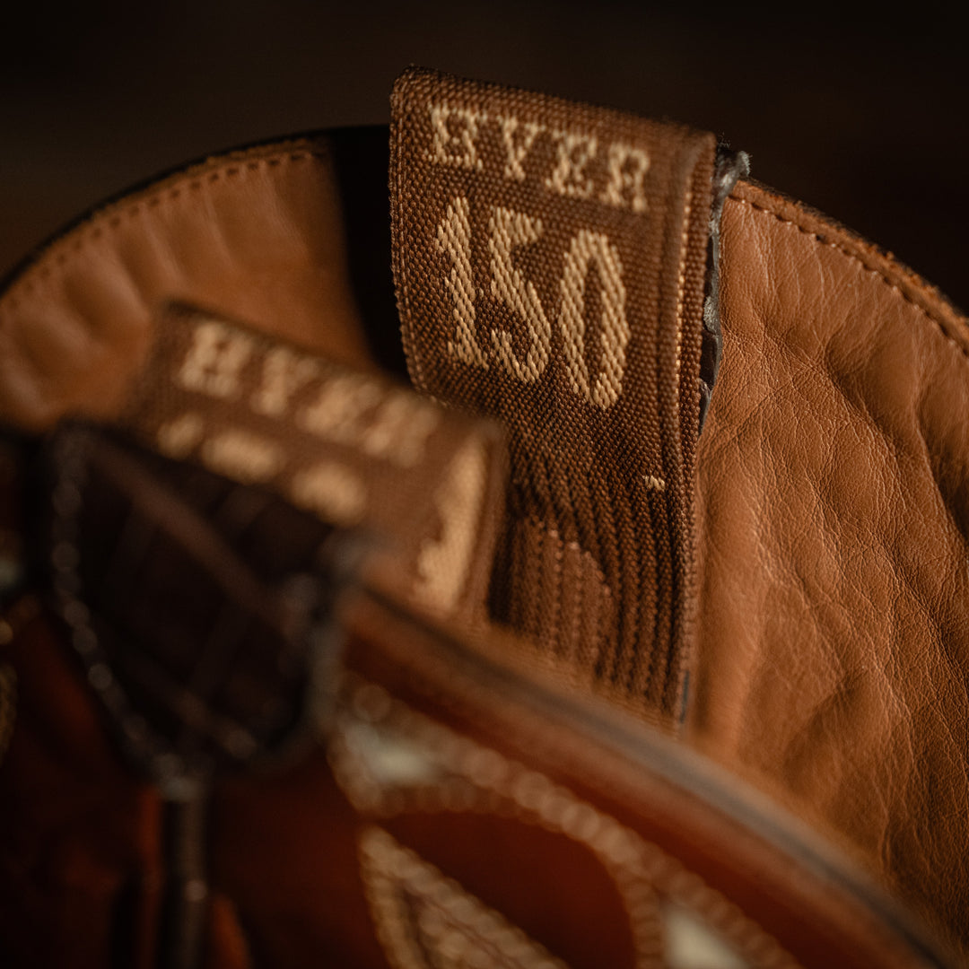 Close-up of a brown leather bag with 'Hyer 150' stitching detail.
