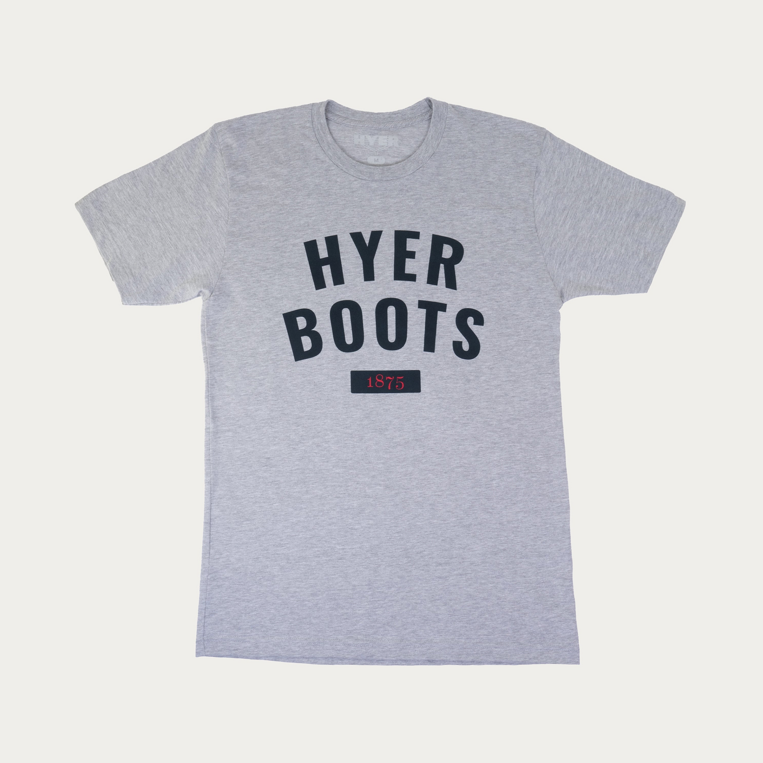 A heather gray crewneck t-shirt featuring the text 'HYER BOOTS' in dark navy blue arched lettering on the chest, with a small dark navy box below containing the year '1875' in red. The shirt is displayed flat against a light off-white background.