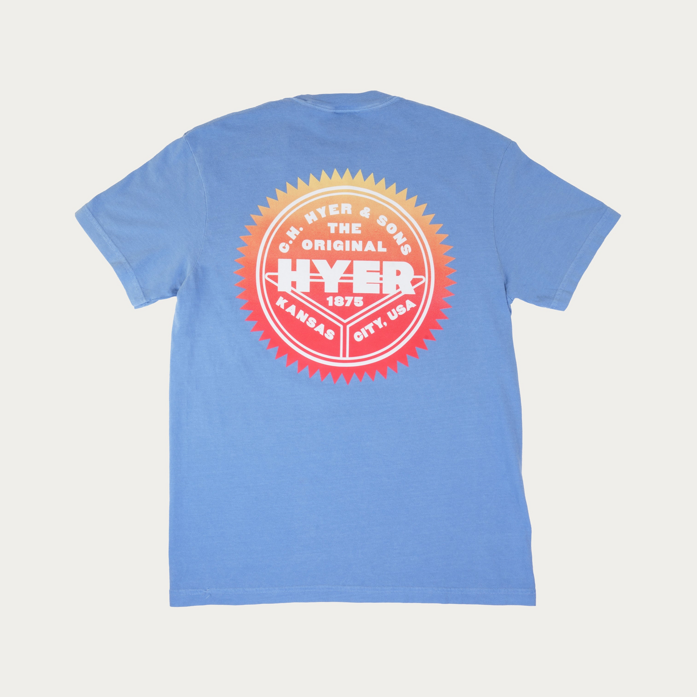 A light blue short-sleeve t-shirt shown from the back, featuring a large circular retro-style graphic in red, orange, and white on the center back.