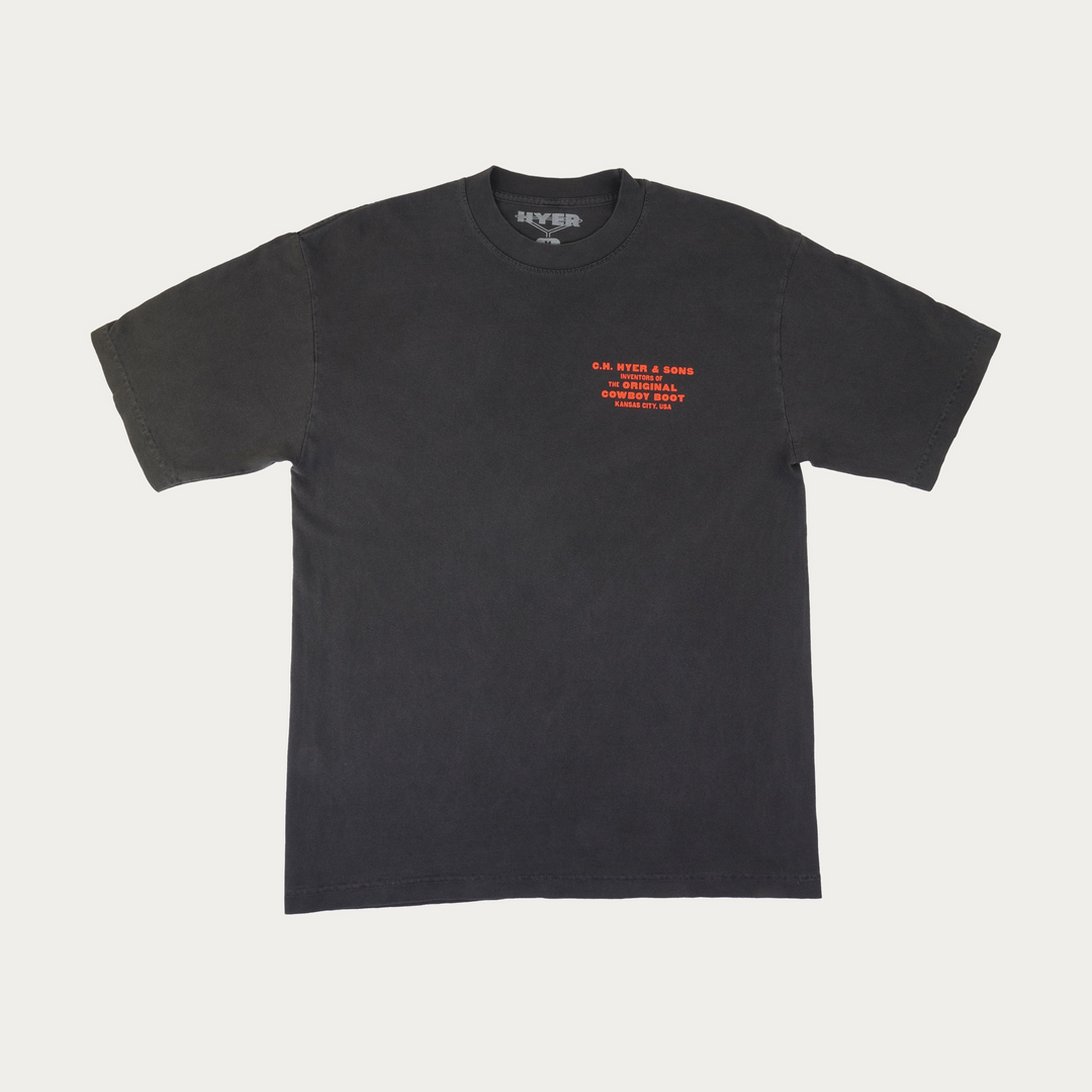 A faded black short-sleeve t-shirt with orange text printed on the left chest, displayed flat against a light gray background.