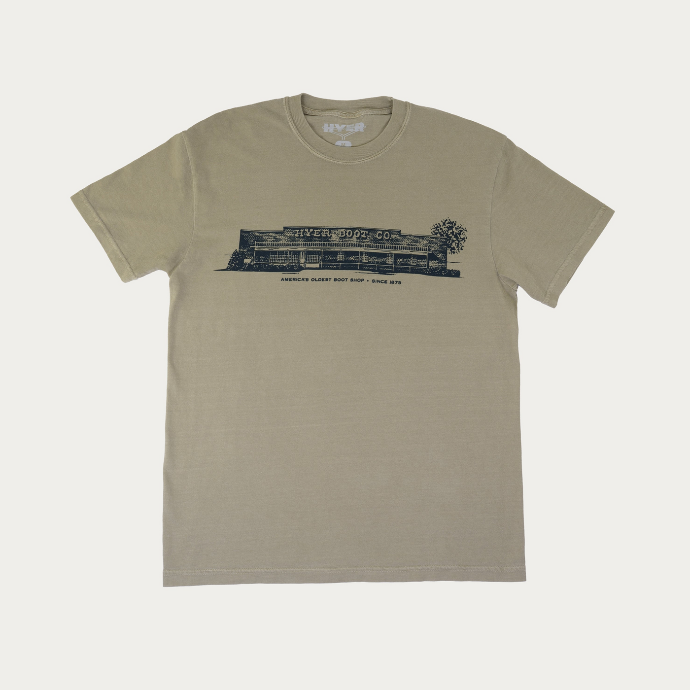 A short-sleeve crewneck t-shirt in a muted khaki-green color, featuring a black graphic print of 'Hyer Boot Co" on the chest, displayed flat against a light off-white background