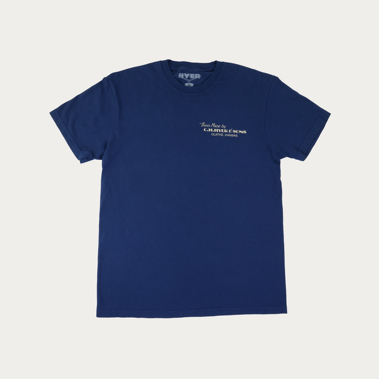 A navy blue short-sleeve crewneck t-shirt with small white text on the left chest reading 'Hand Made by C.H. Hyer & Sons, Olathe, Kansas' and a 'HYER' brand mark printed inside the collar, shown flat on a light gray background.