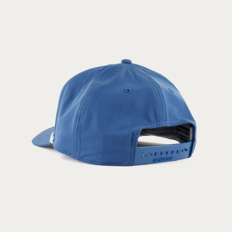 A blue snapback cap shown from the back, featuring a structured crown, a curved brim, and an adjustable hook-and-loop closure, set against a plain off-white background