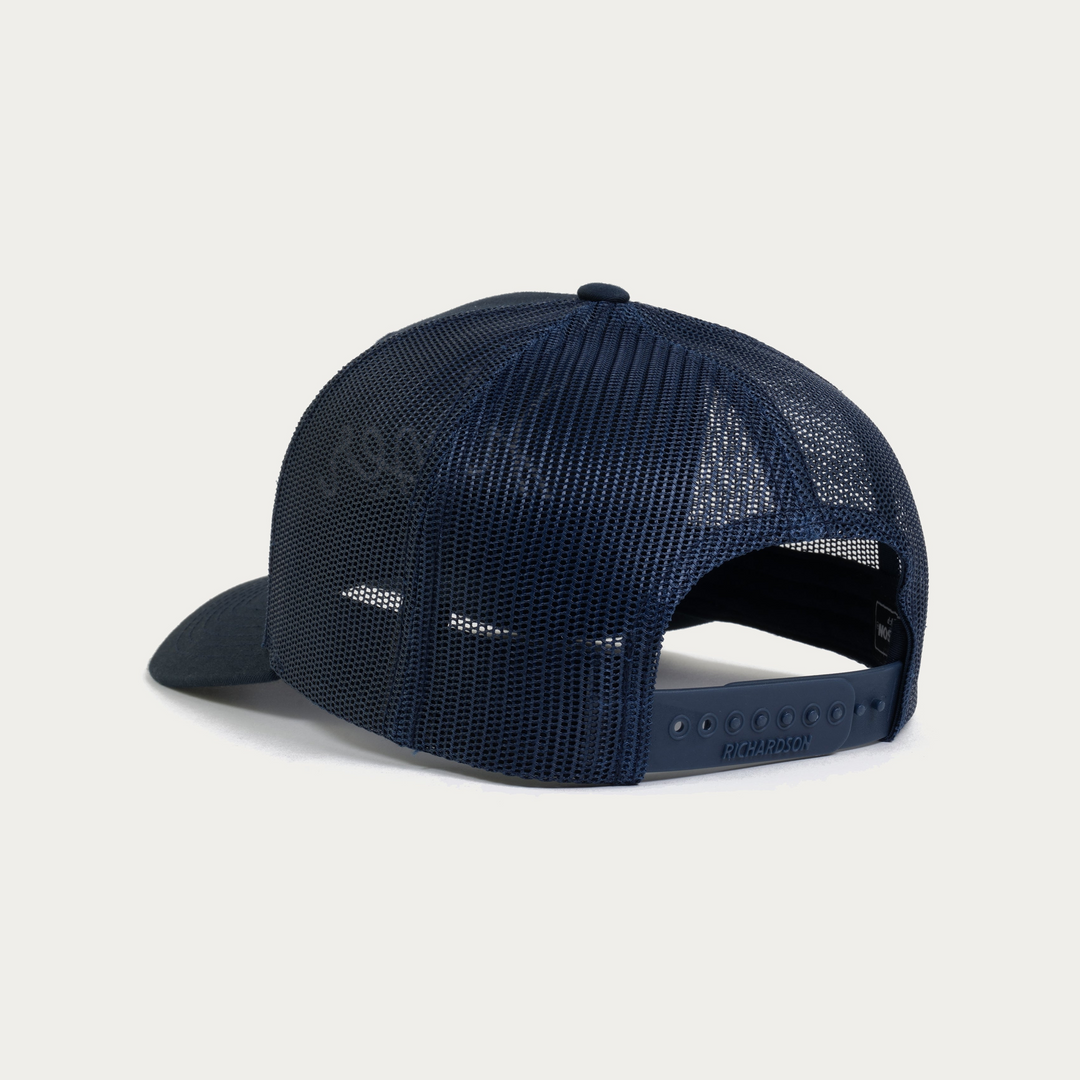 A navy blue trucker cap shown from the back, featuring a dark mesh back and a solid navy brim, photographed against a clean off-white background.