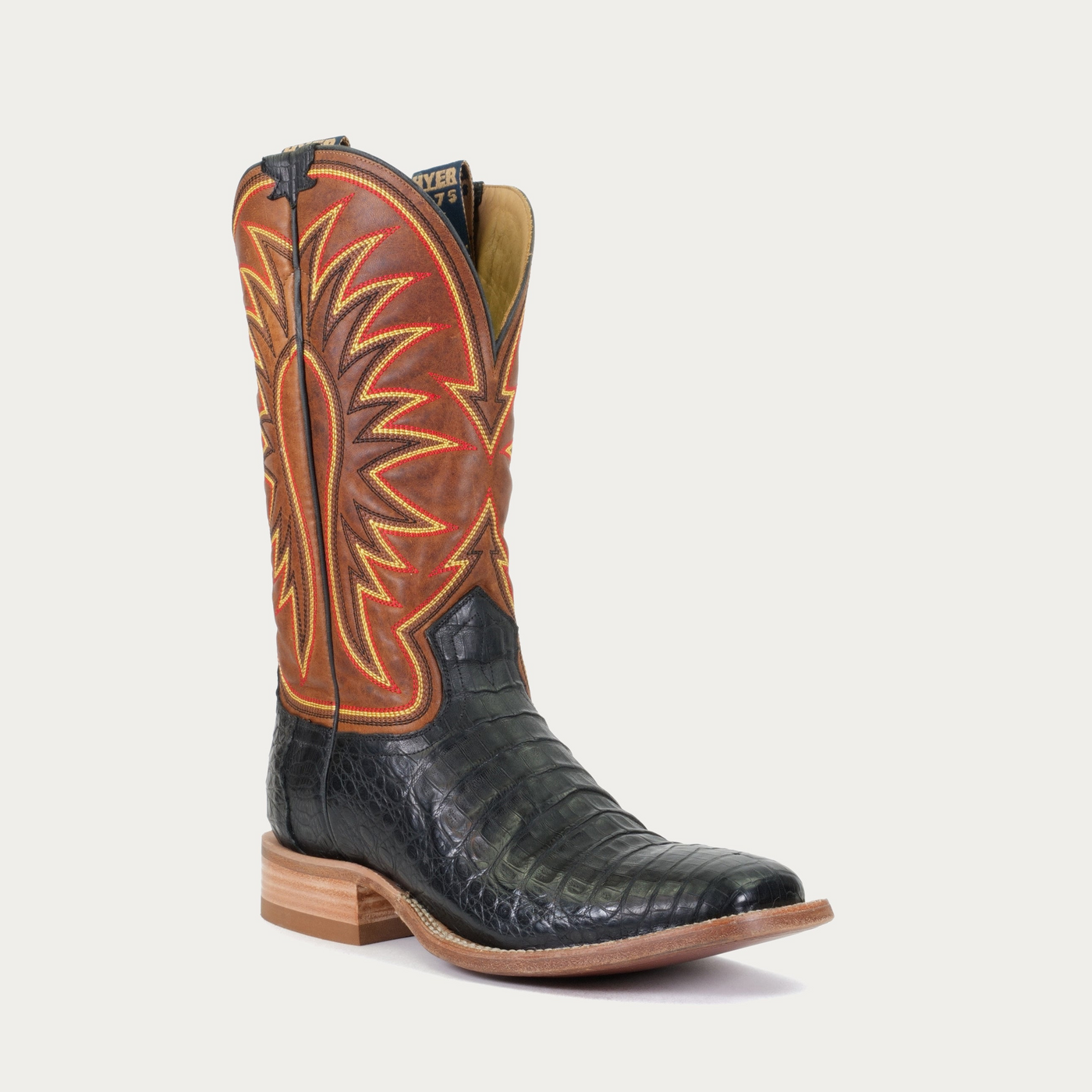 A black and brown cowboy boot with an intricate black, yellow and red stitching design