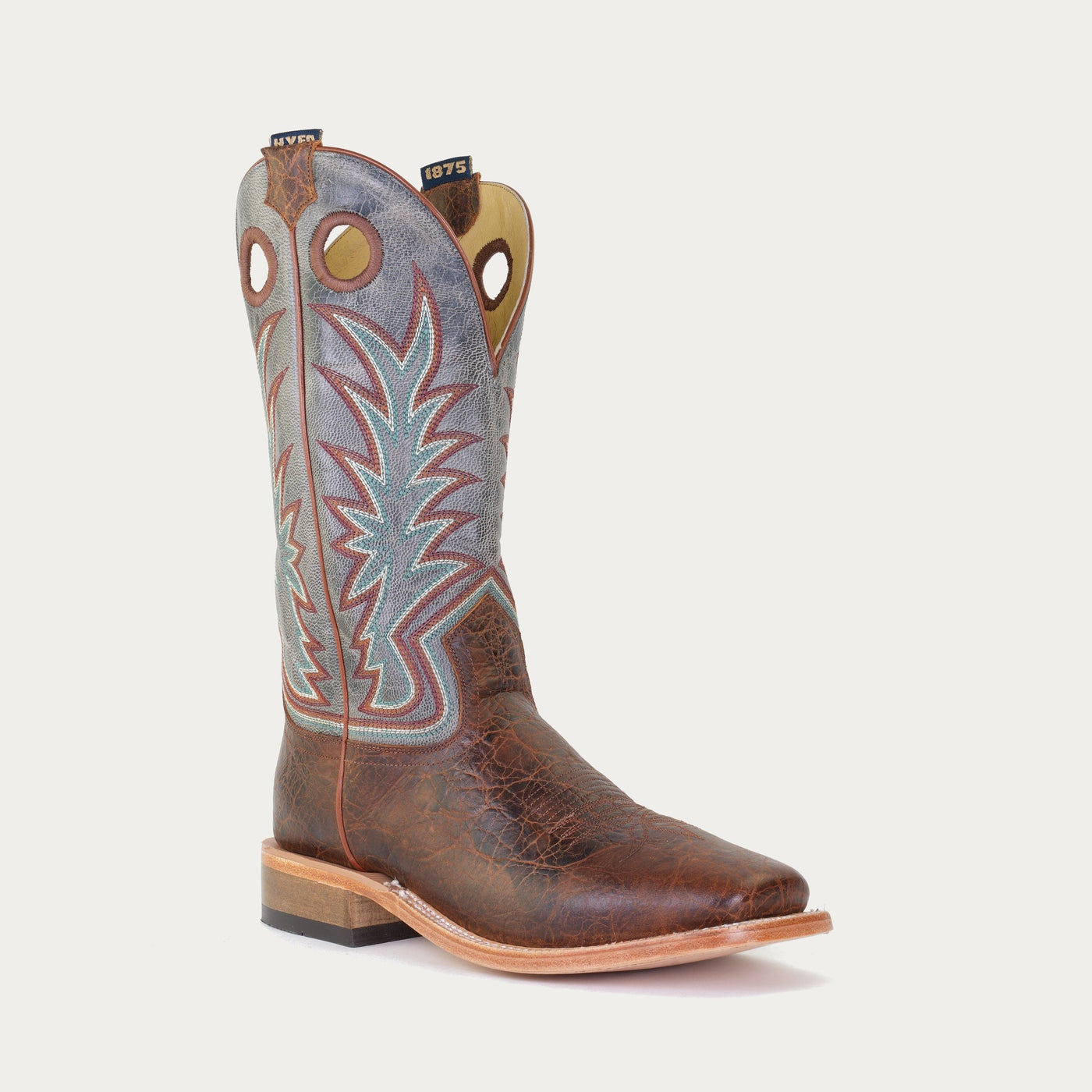 A brown and blue boot with a geometric stitching on the shaft and a square toe.