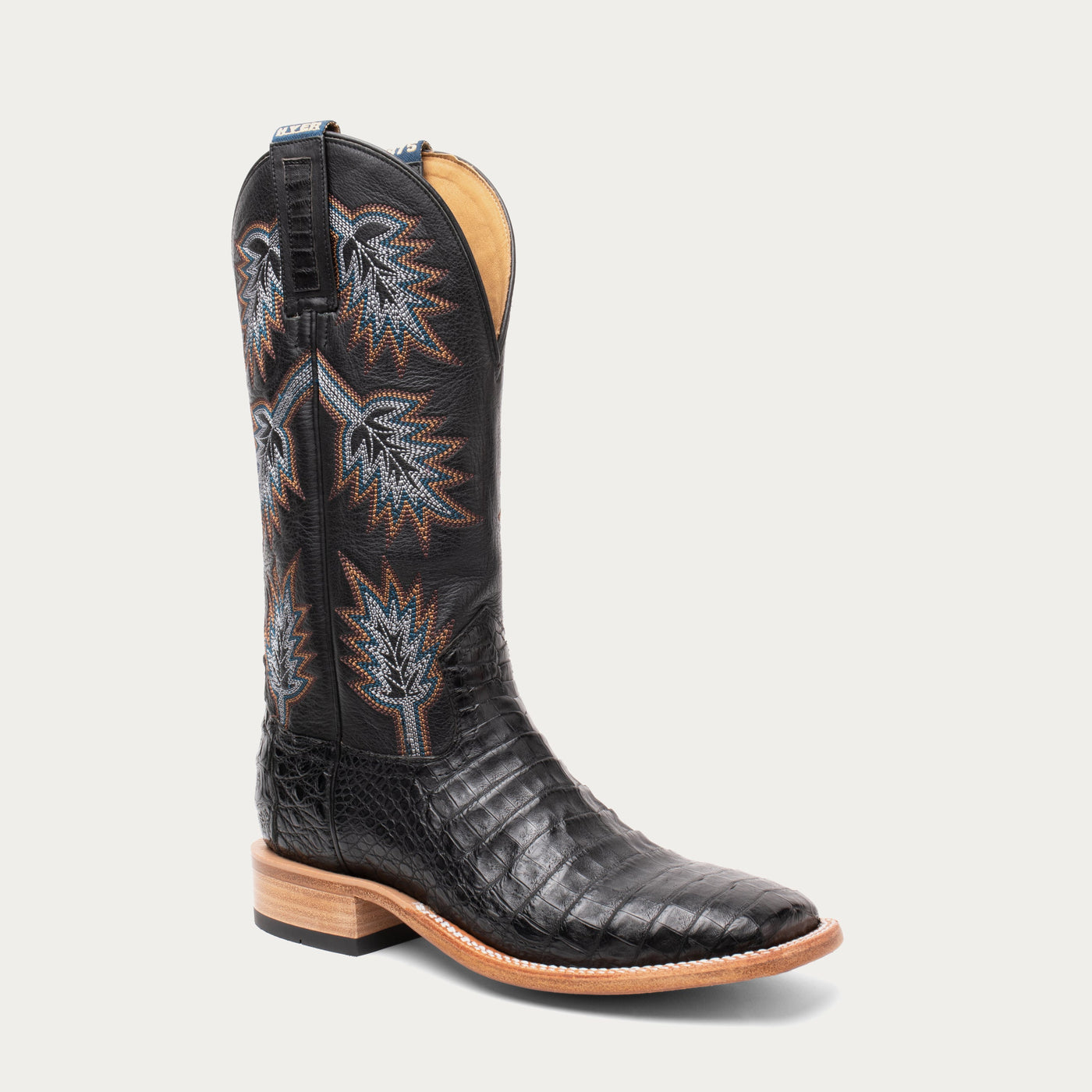 Black caiman cowboy boot with intricate stitch patterns on a white background