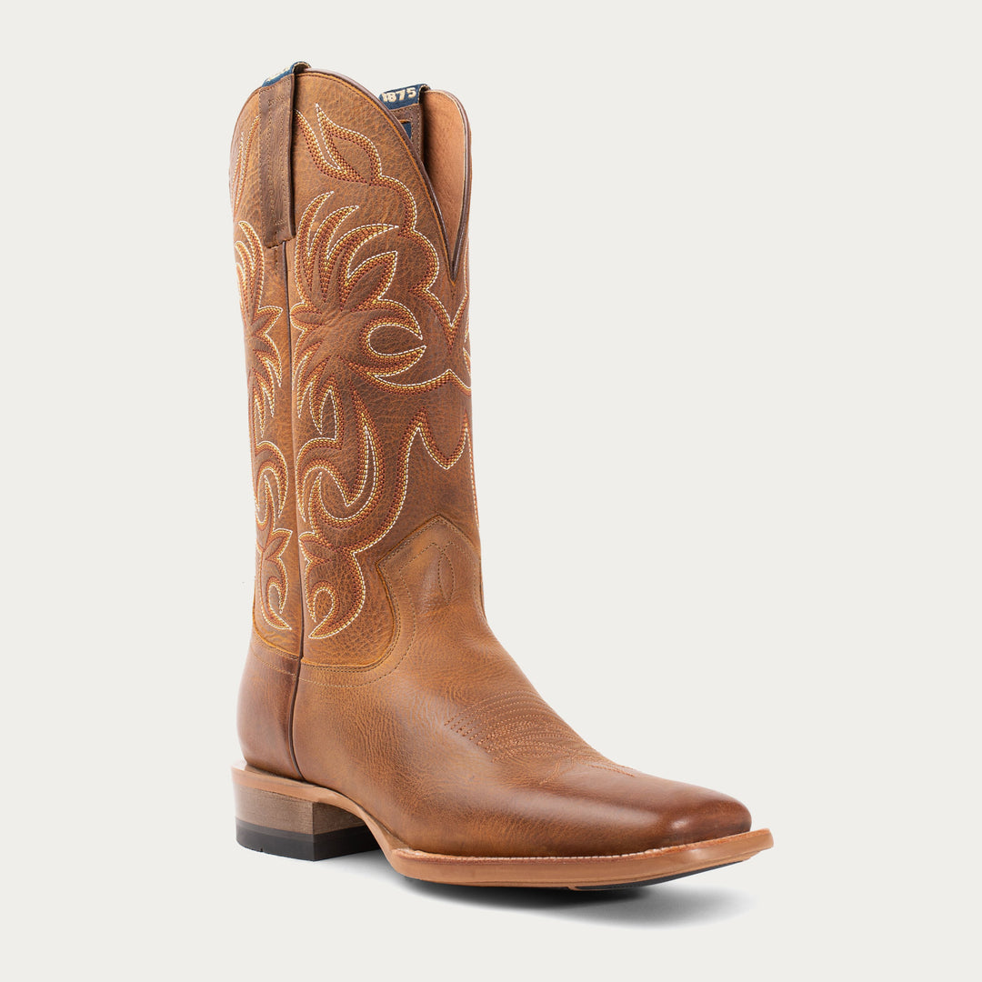 Brown cowboy boot with intricate white stitching on a light gray background