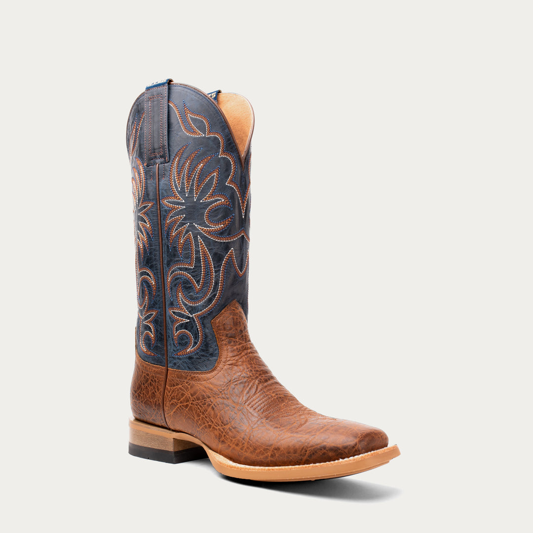 Brown cowboy boot with intricate black and brown design on a light gray background