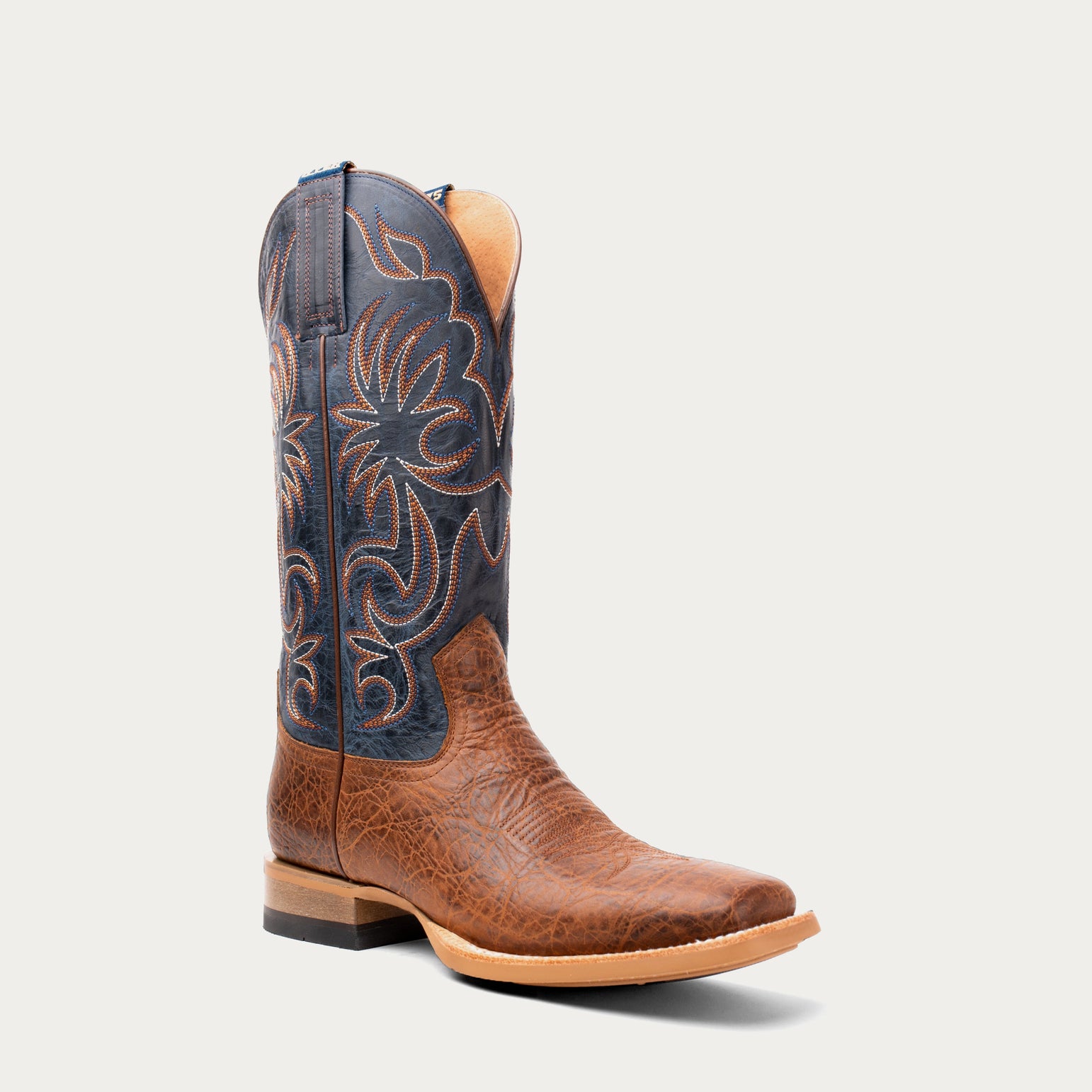 Brown cowboy boot with intricate black and brown design on a light gray background