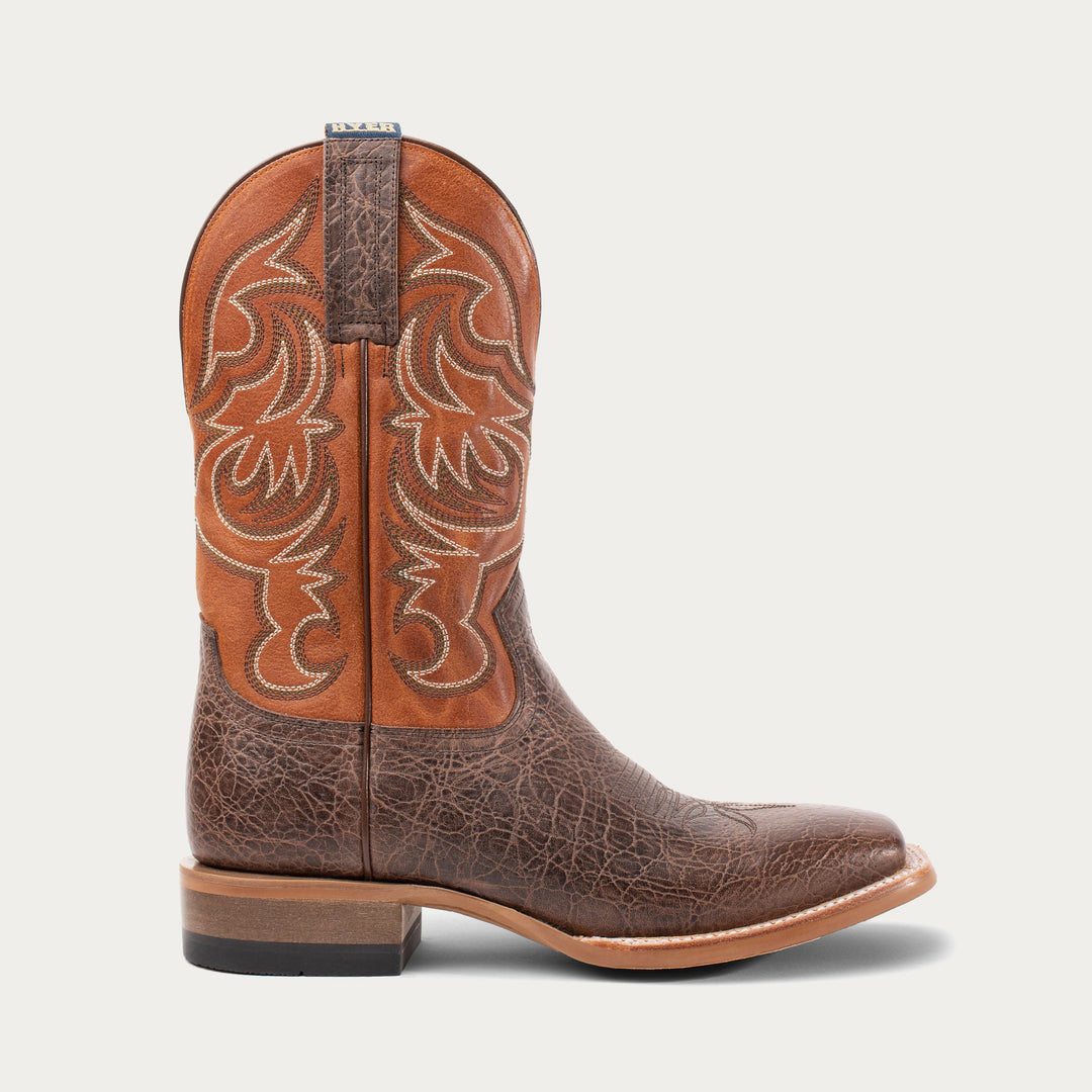 Brown cowboy boot with intricate design on a light gray background