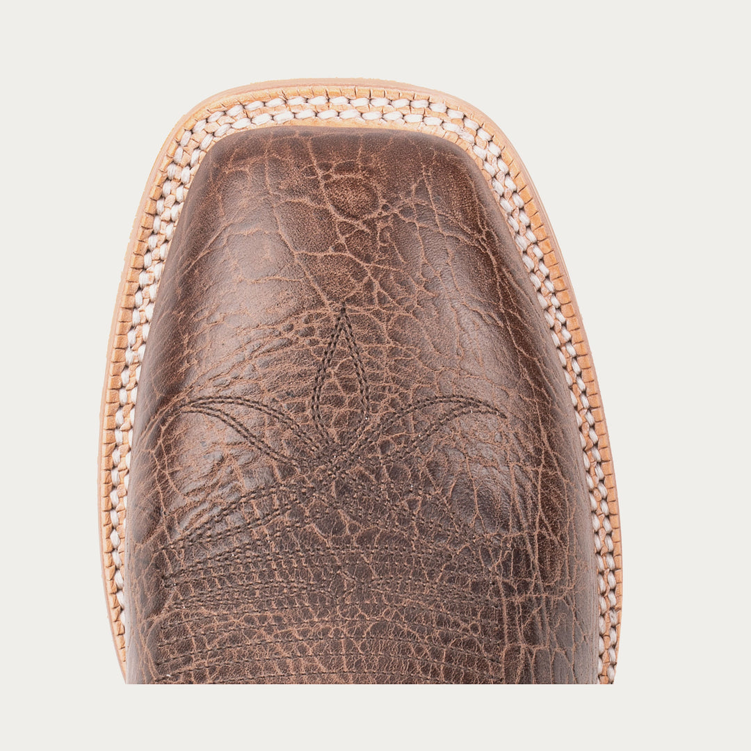 Close-up of a brown leather boot sole with intricate patterns on a light gray background