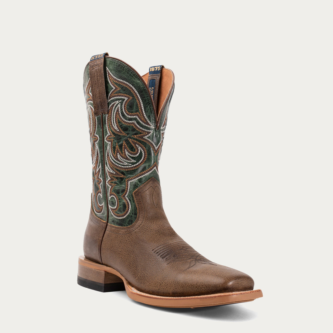 Brown cowboy boot with green intricate design on a light gray background