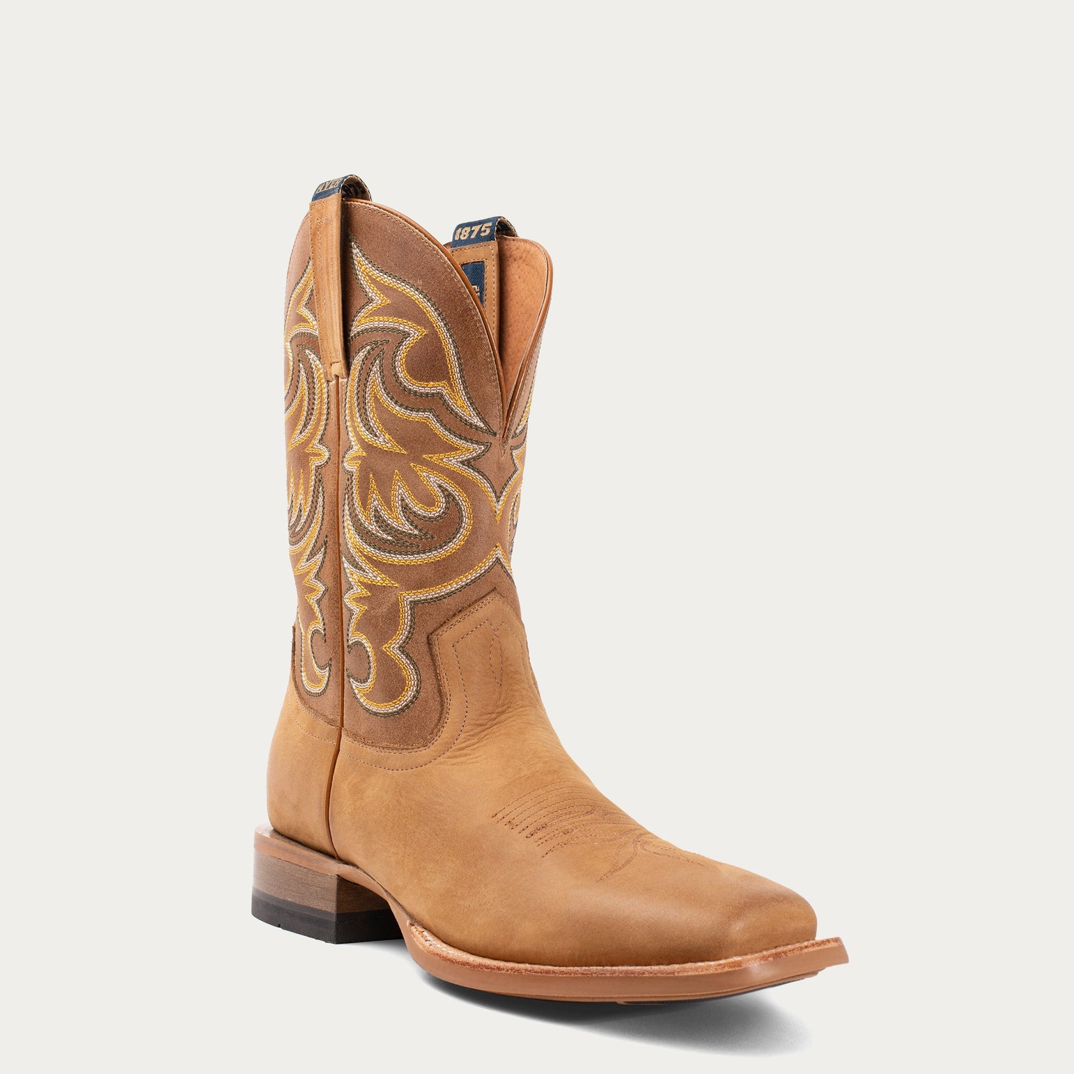 Tan cowboy boot with intricate stitching on a light gray background