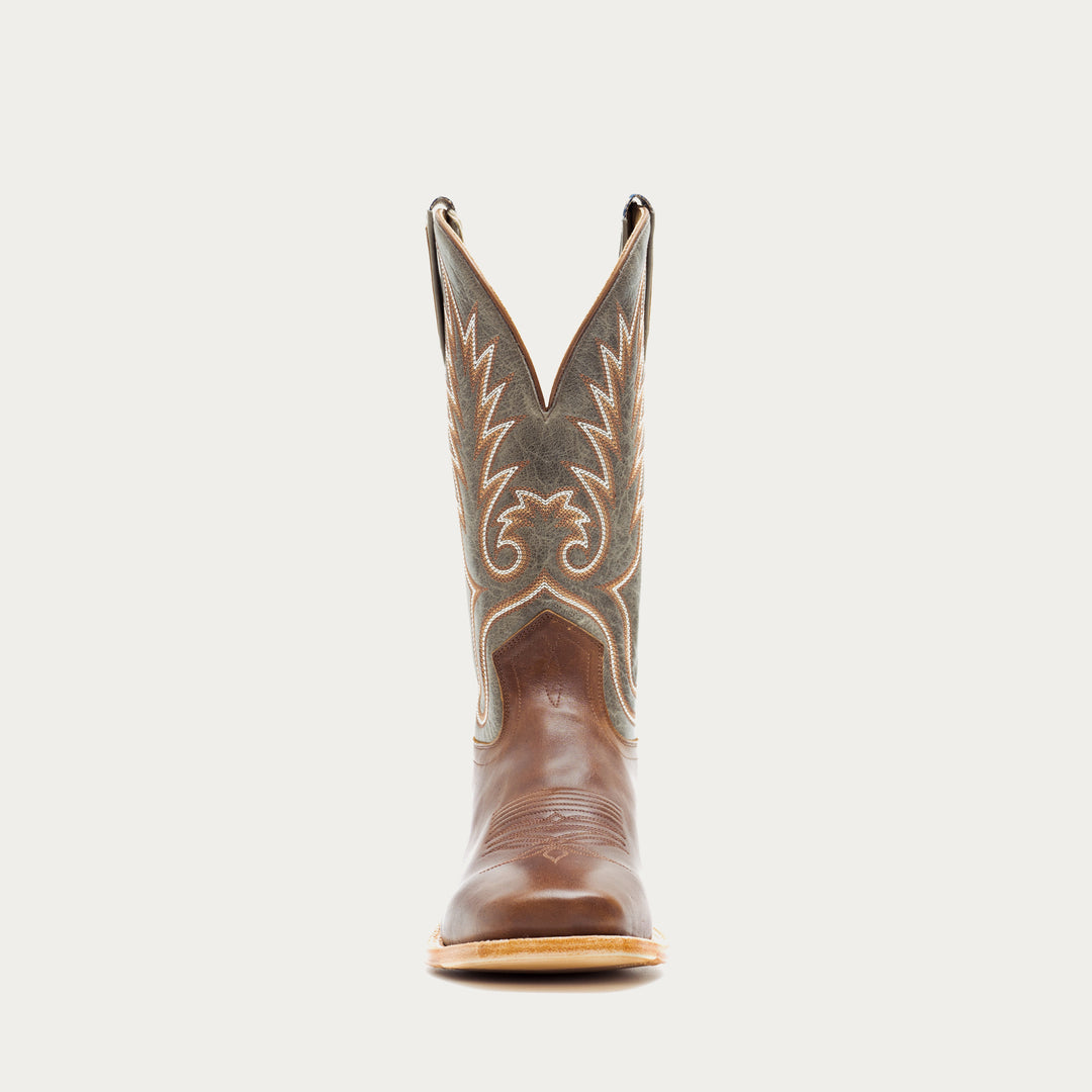 Brown and green cowboy boot with decorative pattern on a light gray background