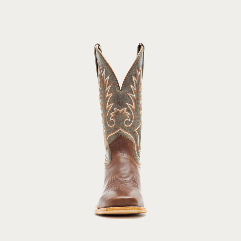 Brown and green cowboy boot with decorative pattern on a light gray background