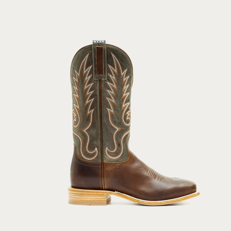 Brown and green cowboy boot with intricate white stitching on a light gray background