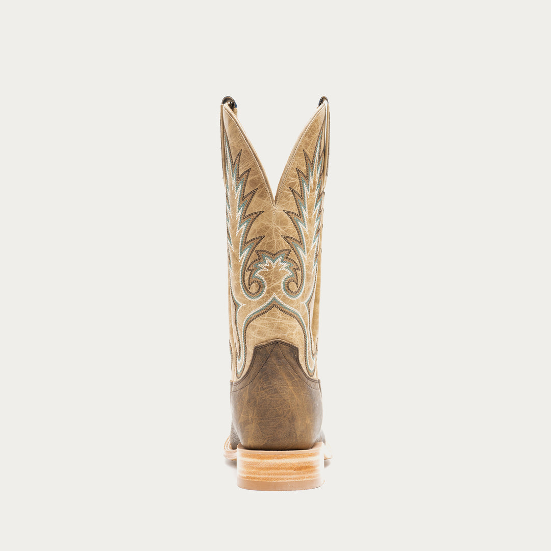 Brown and tan cowboy boot with intricate design on a light gray background