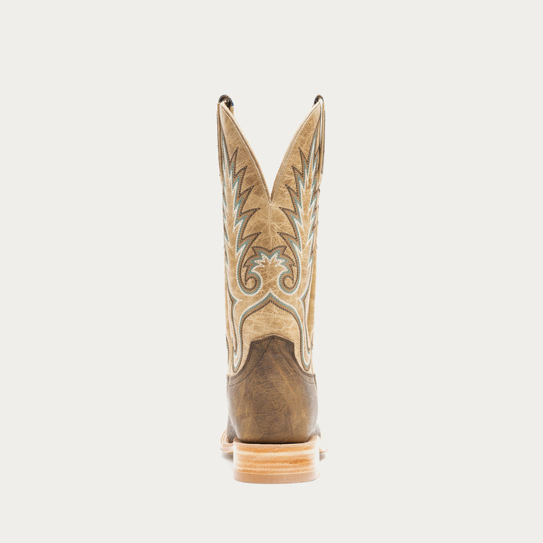 Brown and tan cowboy boot with intricate design on a light gray background