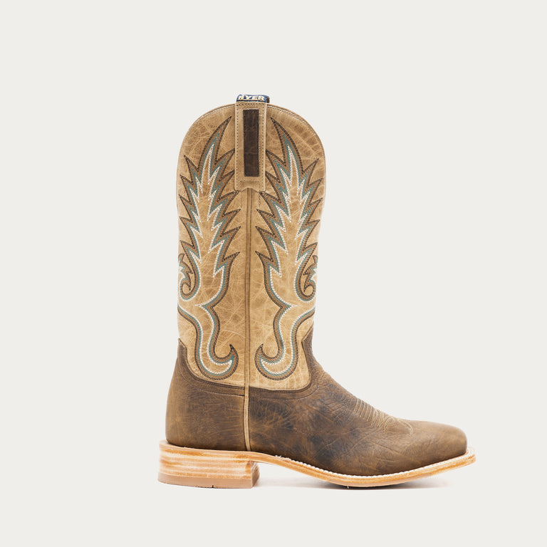 Brown and tan cowboy boot with intricate design on a light gray background