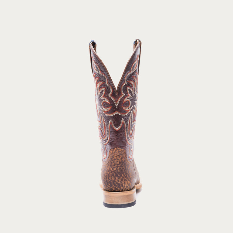 Brown cowboy boot with white and red intricate stitching on a light gray background