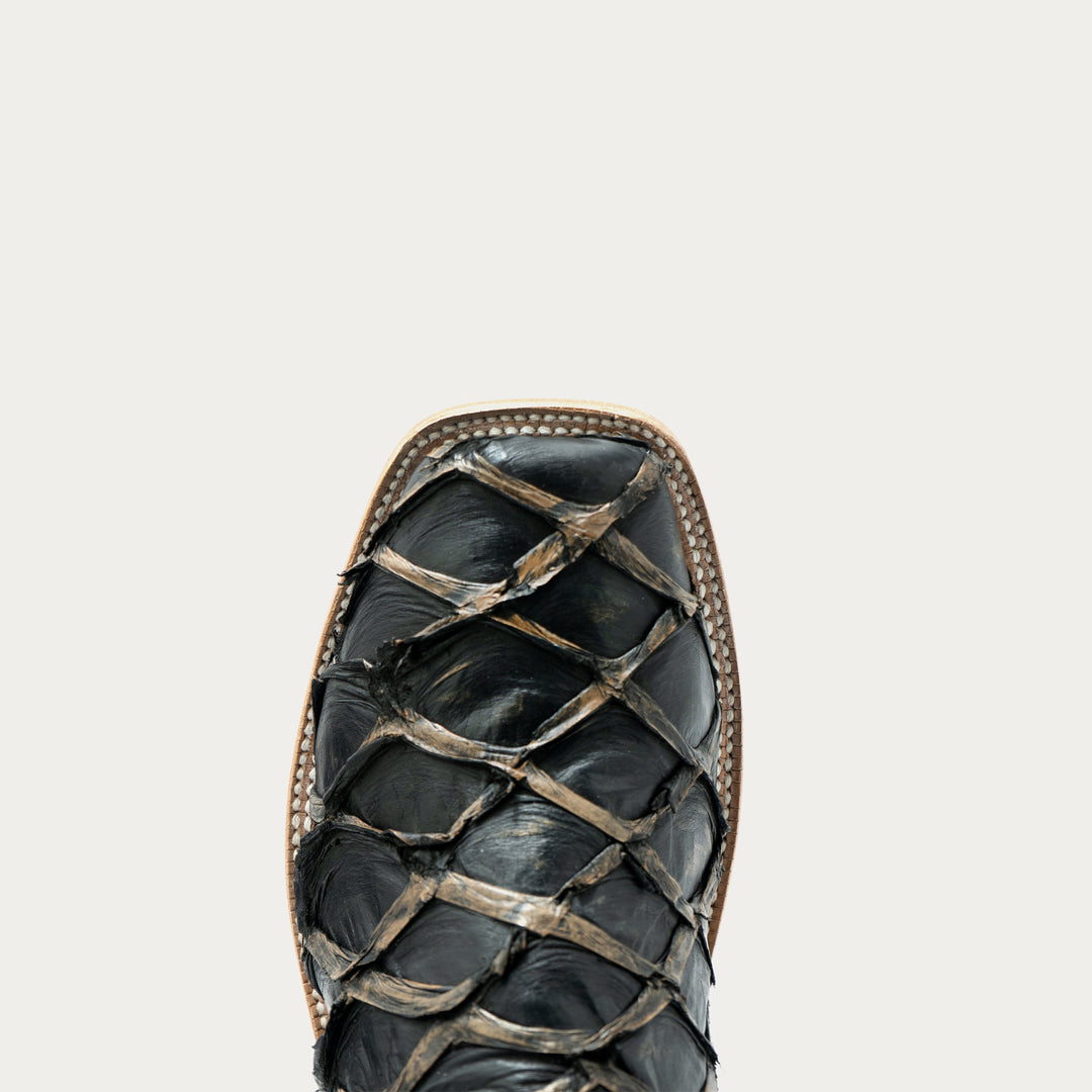 Close-up of the toe of a black leather cowboy boot with a big bass vamp and a tan stitched edge, shown on a white background.