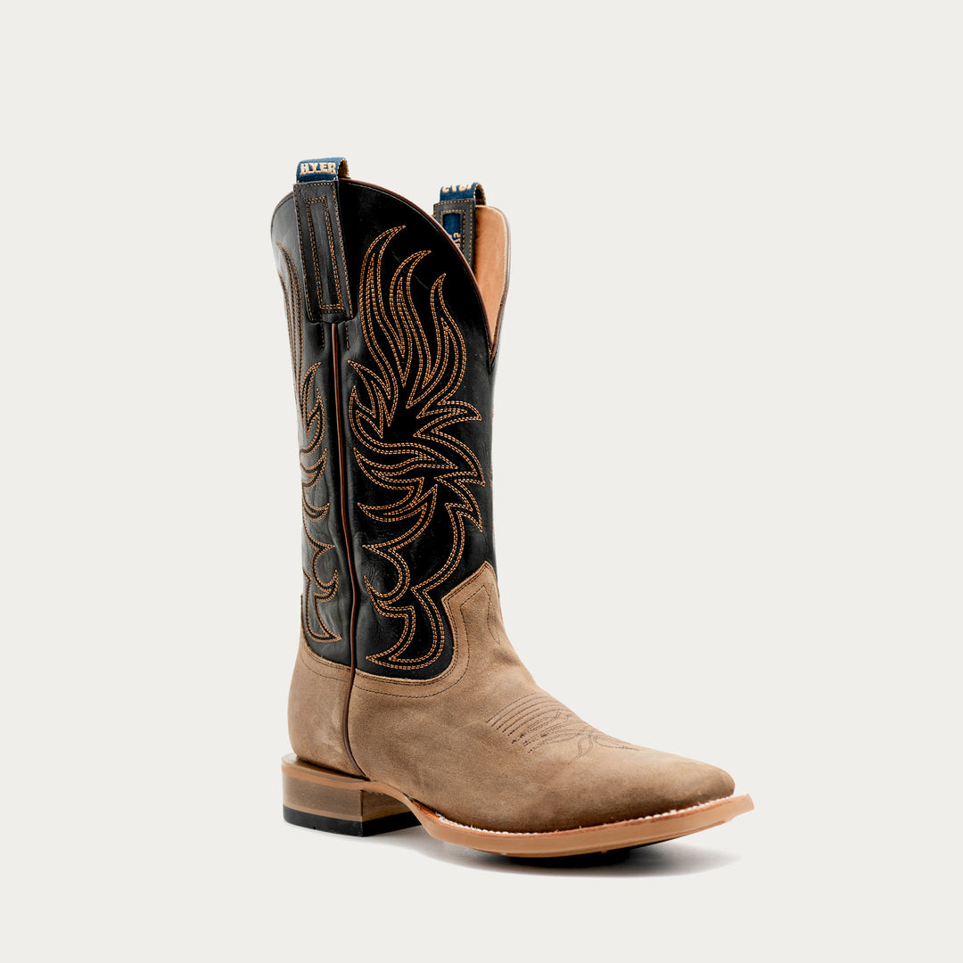 A single western cowboy boot shown in a side profile on a clean white background. The boot features a tan suede lower section and a black leather shaft with intricate tan embroidery.