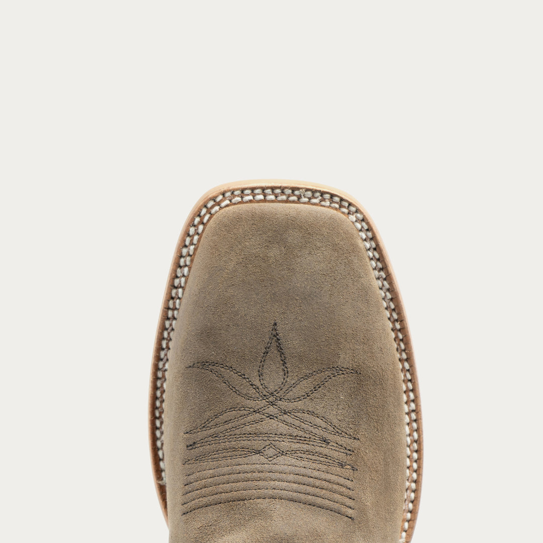 Top-down view of a western boot toe in taupe suede, featuring decorative stitching and a braided edge on a light gray background.