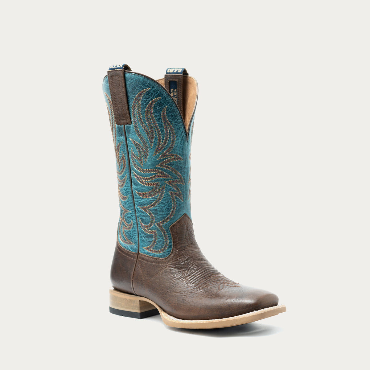 A single western cowboy boot with a brown leather vamp, a turquoise blue shaft featuring brown embroidered patterns, and a low stacked block heel, shown against a light gray background.