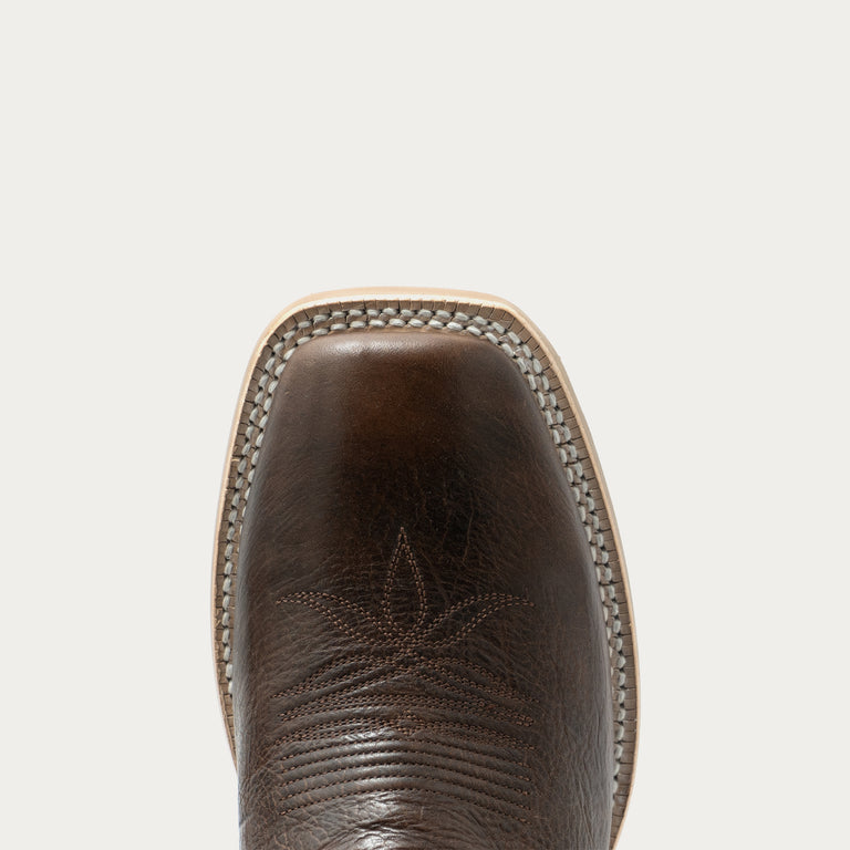 Close-up top view of a brown leather cowboy boot showing the square toe, stitched edge, and western-style stitching on a light gray background.