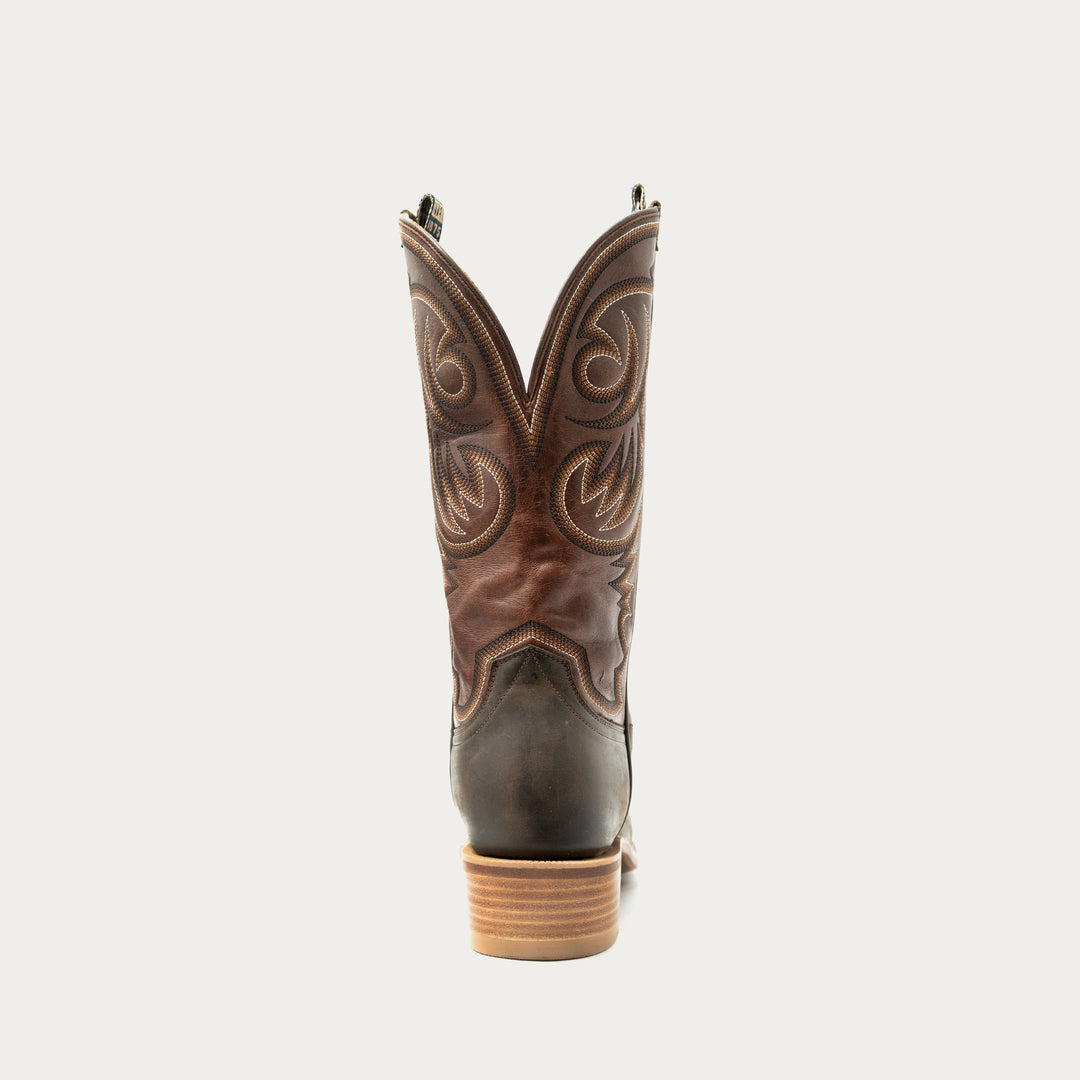 Brown cowboy boot with intricate designs on a white background