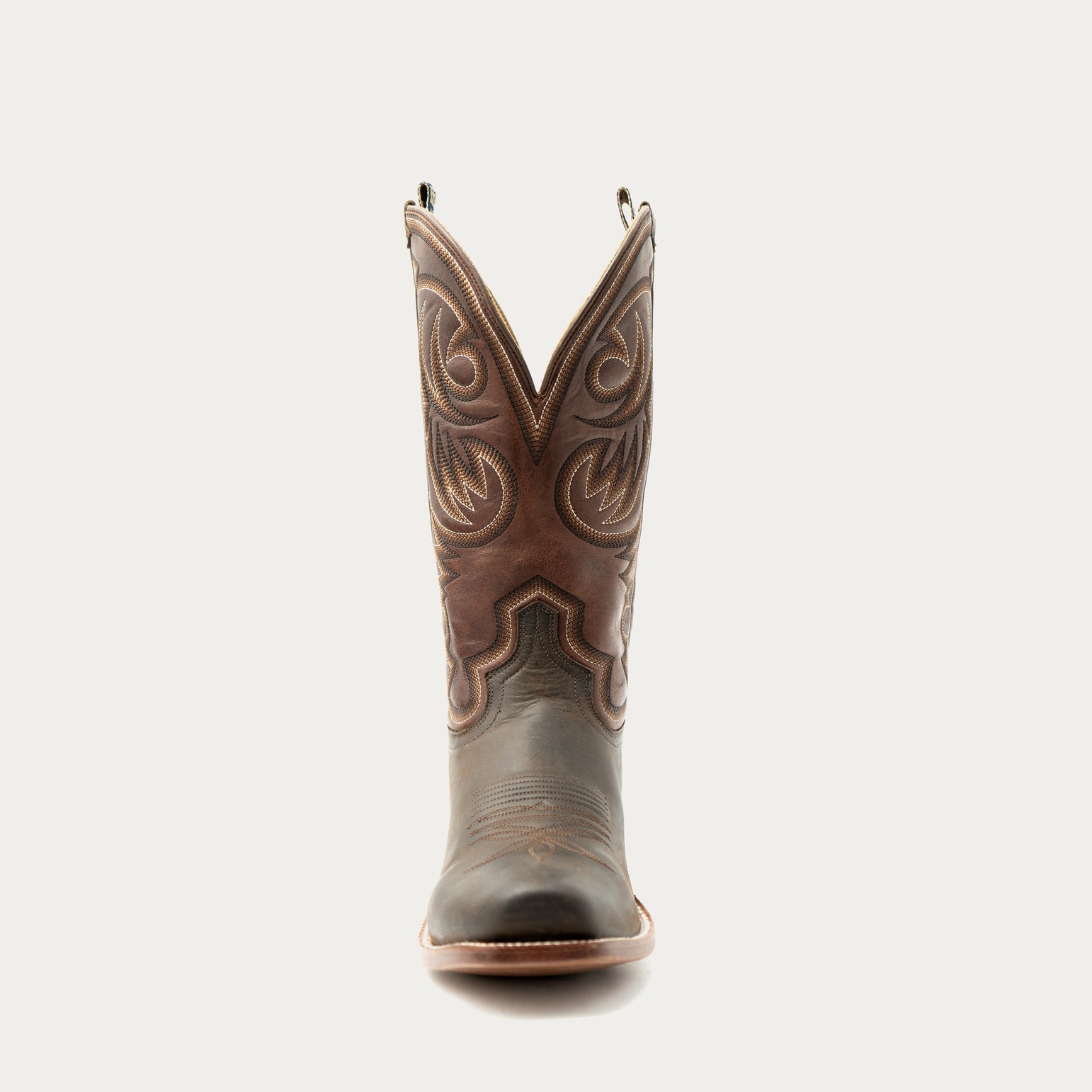 Brown cowboy boot with intricate designs on a white background