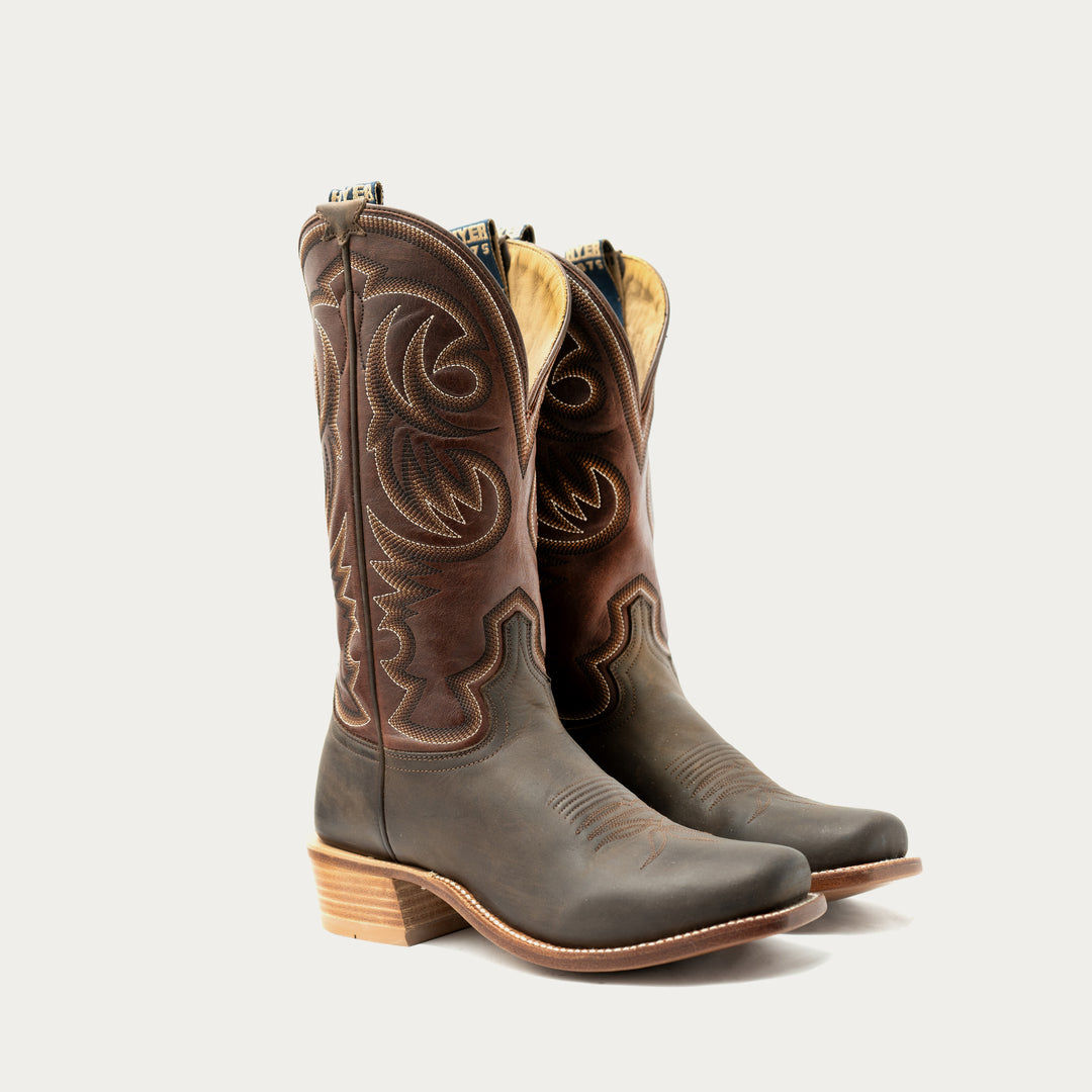 Pair of brown cowboy boots with intricate designs on a light gray background