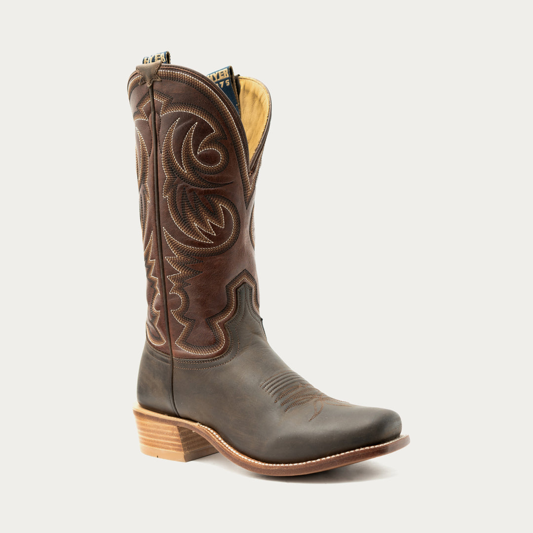 Brown cowboy boot with intricate stitching on a light gray background