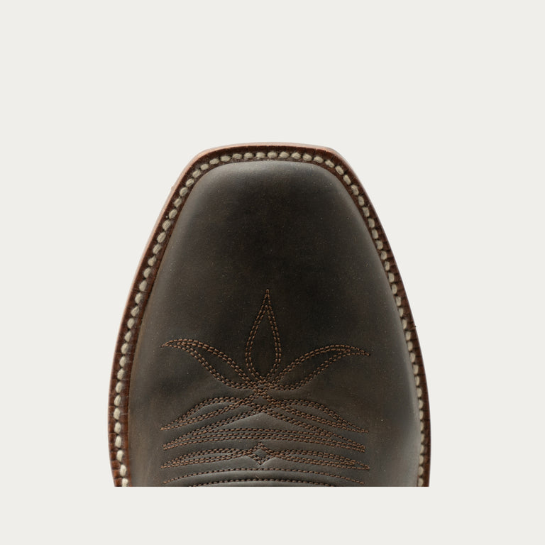 Brown leather boot with intricate stitching on a light gray background