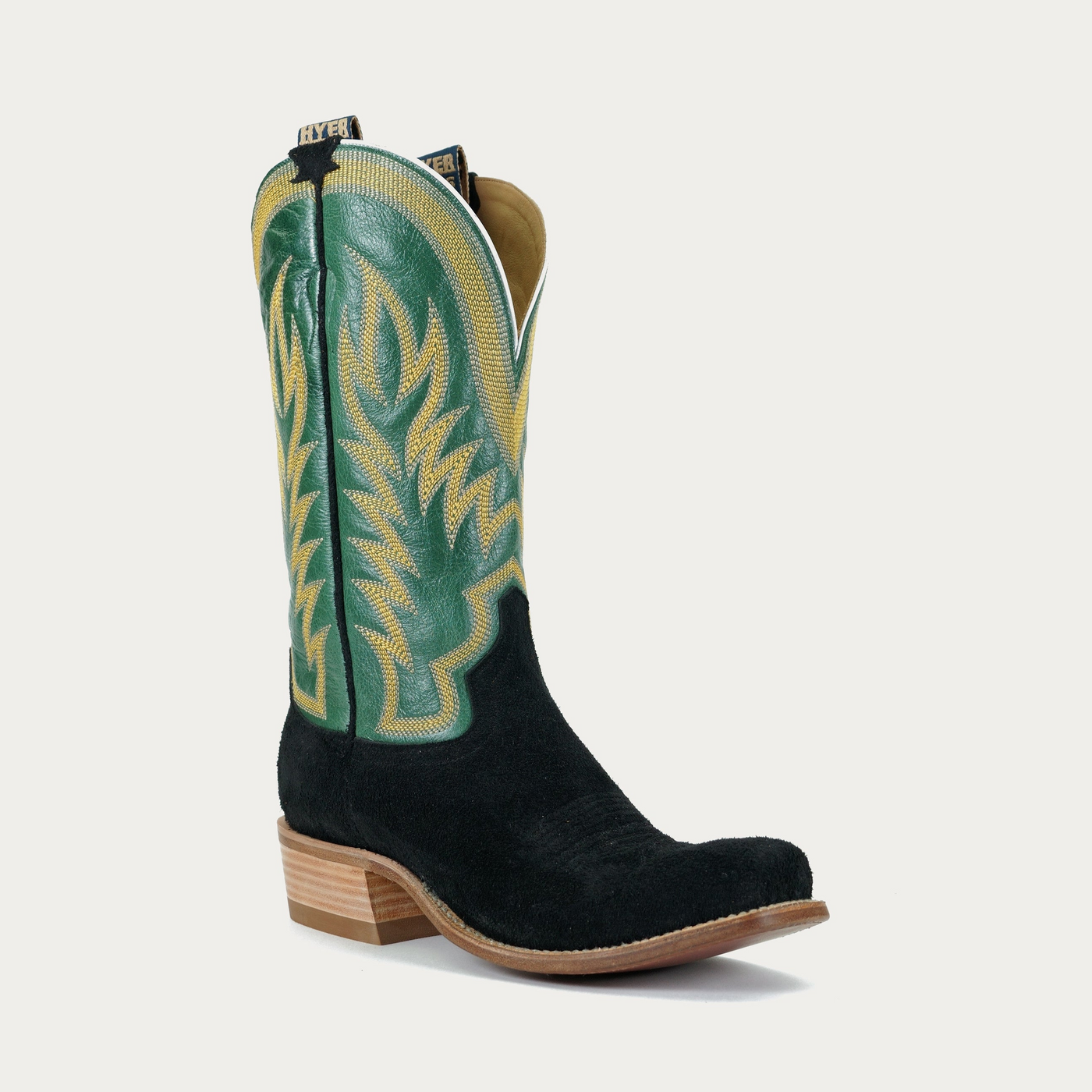 A black and green cowboy boot with intricate yellow stitching on the shaft.