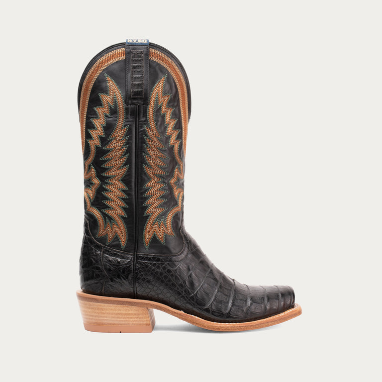 Black cowboy boot with brown accents on a light gray background