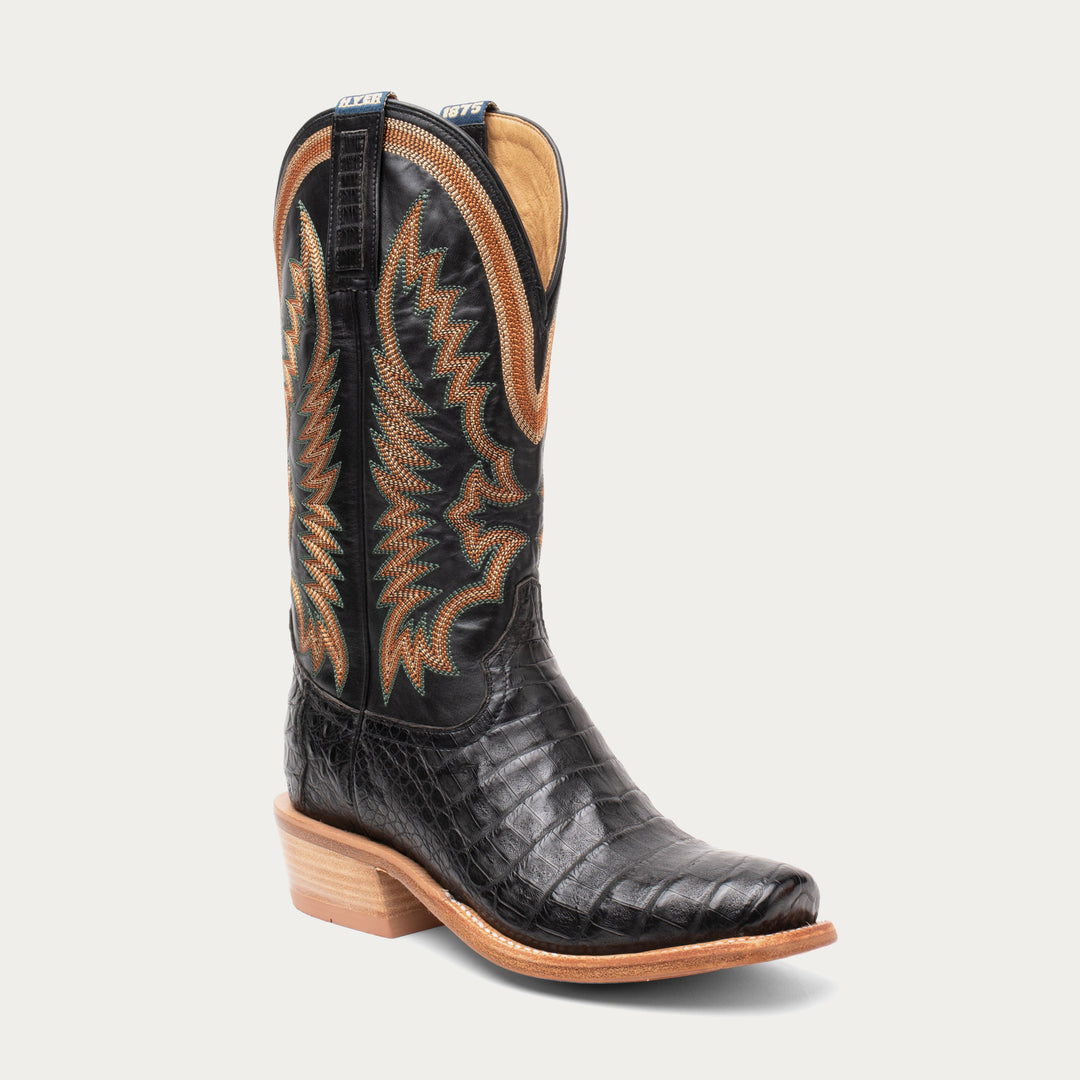 Black cowboy boot with brown stitching on a light gray background