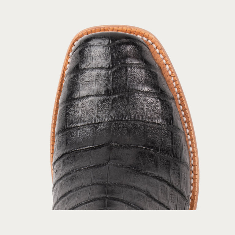 Close-up of a black leather shoe with brown trim on a light gray background